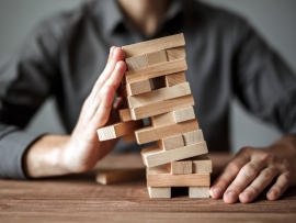 Businessman holds the model of business, made from wood blocks. Alternative risk concept, business plan and business strategy. Insurance concept.